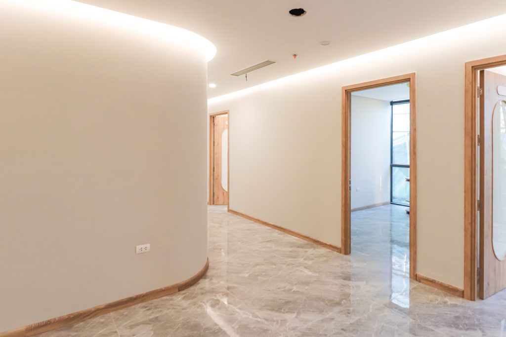 Bright, minimalist corridor with marble flooring and wooden door frames in a modern office setting.